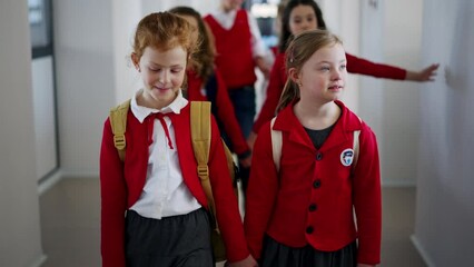 Canvas Print - Happy schoolgrirl with Down syndrome in uniform walking in scool corridor with classmates.