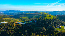 Wind Farm Generating Green Energy. Wind Turbines With Blades In Field Aerial View. Alternative Energy. Scenic Aerial View Of Wind Turbines Farm Over Green Beautiful Landscape.