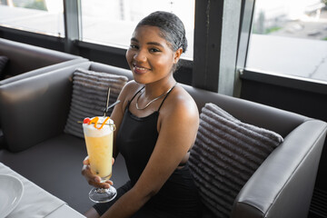 beautiful young african woman in a restaurant with a cocktail	
