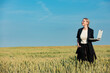 © Simonforstock - employee of an agricultural firm with a laptop checks the quality of wheat in the field