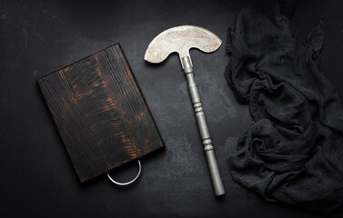 Wall Mural - Rectangular empty wooden cutting board and kitchen knife on black table with gauze napkin, top view