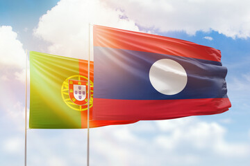 Sunny blue sky and flags of laos and portugal