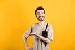 © platinumArt - Cheerful young man wearing t-shirt posing isolated over yellow background smiling cheerfully, feeling happy and showing a concept in copy space with palm of hand