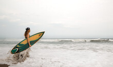 Caucasian Surfer Woman Holding A Surfboard And Entering The Sea Ready To Surf The Waves