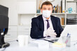 © JackF - Focused male in disposable personal protective equipment working in business office using laptop, new normal due to coronavirus outbreak