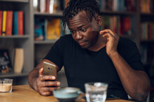African American Man Using Smartphone While Drinking Coffee In A Cafe
