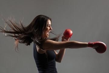 Wall Mural - beautiful girl exercising karate punch and screaming against gray background. .