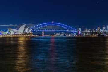 Wall Mural - Colourful Light show at night on Sydney Harbour NSW Australia. The bridge illuminated with lasers and neon coloured lights. Sydney laser light show