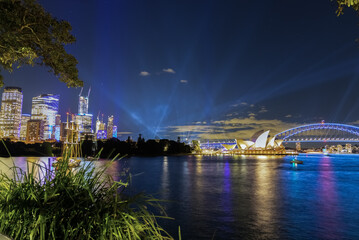 Colourful Light show at night on Sydney Harbour NSW Australia. The bridge illuminated with lasers and neon coloured lights. Sydney laser light show