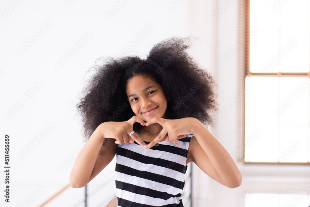 Happy young african girl with curly hair looking to camera at home ...