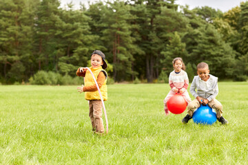 Wall Mural - childhood, leisure and people concept - group of happy children playing with hopper balls and hula hoop at park