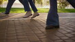 © stockbusters - Legs walking paving street close up. Family enjoying warn sunny evening in park.