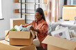 © Syda Productions - moving, people and real estate concept - happy smiling woman unpacking boxes sitting on sofa at new home