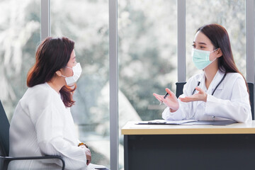 Asian elder female consults with professional doctor about her symptom or health problem in examination room at hospital.