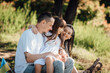 © Denys Poliakov - Young family during an outdoor walk, sitting on the lawn, smiling and having fun