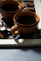 Wall Mural - fresh black coffee in a cups and chocolate on blackboard, closeup vertical