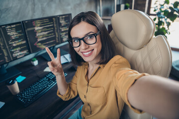 Self-portrait of beautiful cheerful skilled girl cyber editor developer showing v-sign intranet web at workplace workstation indoors