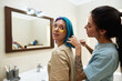 Girl combing colorful hair with comb of girlfriend