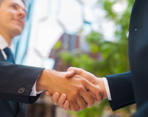 Wall Mural - Confident businessman and his colleague are shaking hands in front of modern office building. Financial investors outdoor. Banking and business.