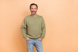 © deagreez - Portrait of attractive cheerful man holding hands in pockets copy space isolated over beige pastel color background