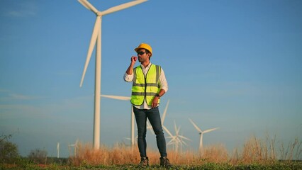 Wall Mural - Engineer wearing uniform ,helmet inspection and survey work in wind turbine farms rotation to generate electricity energy. Green ecological power energy generation wind sustainable energy concept.