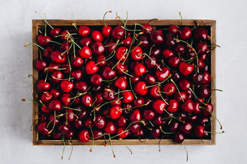 Wall Mural - Cherry. Sweet Cherries in wooden box or crate on white stone concrete background. Top view.