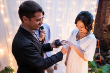 Diverse Bride And Groom Exchanging Rings Near Wedding Arch