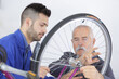 senior talking to apprentice while fixing bike wheel