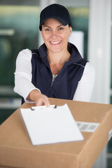 cheerful delivery woman smiling holding out cardboard box