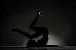 © Nikola Spasenoski - Fit ballerina girl lying and stretching practicing yoga poses. Side lit silhouette against dark background.. .