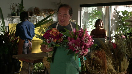 Portrait of an Asian florist holding two bouquet of flowers standing inside flower shop. Small business store entrepreneurship