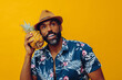 © Carlos David - handsome mid adult bearded african american man in Hawaiian shirt posing with pineapple as telephone looking up on yellow background studio