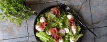 Plate With Salad With Prosciutto, Avocado, Radish And Quail Eggs On A Dark Table