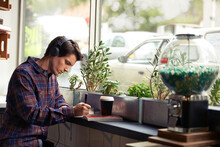 Hipster at work. Shot of a young man studying in a cafe and listening to music.