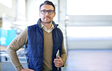 Poster - Taking care of warehouse business. Portrait of a manager holding a digital tablet while standing on the factory floor.