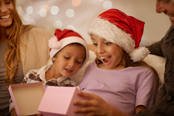 Poster - Just what I wanted. A little girl unwrapping a Christmas present while surrounded by her family.