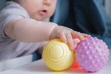 Baby Holding A Colorful Sensory Soft Ball For Babies And Kids. Concept Of Massage Textured Balls For Developing Tactile Senses. 