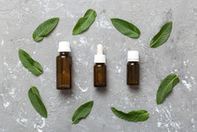 Natural Mint Essential Oil In A Glass Bottle. Organic Cosmetics With Herbal Extracts Of Mint On Colored Background