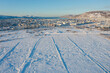 Seaside port town. Winter aerial view of a snow-covered field and the city of Magadan. Nagaev Bay in the distance. Cold winter weather. Magadan region, Siberia, the Russian Far East.