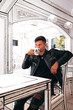 young man in leather jacket drinking coffee in a photogenic white monochrome cafe in japan