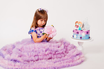 Three years old girl in a pink dress and a birthday cake