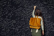 Child girl against big blackboard with formulas, back view