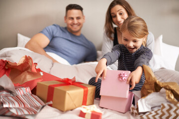 Poster - Oh wow, thanks mom and dad. Shot of a little girl opening presents in bed as her parents watch.