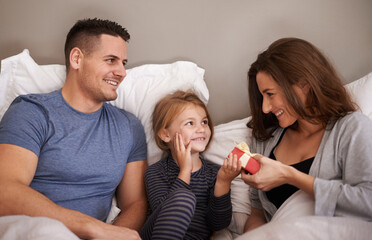 Poster - Thanks mommy. Shot of a little girl receiving presents in bed from her parents.