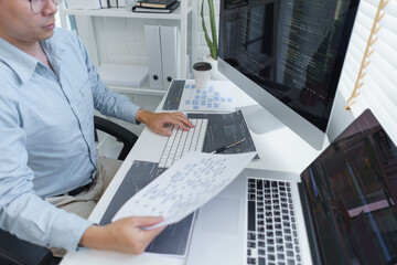Wall Mural - software development concept, male programmer read data on document while programming on computer