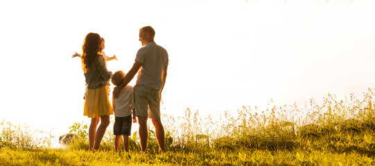 Happy loving family walking outdoor in the light of sunset. Father, mother, son and daughter.