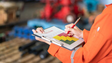 The Manager Is Using Ballpoint Pen To Marking On The Risk Assessment Matrix At "High Risk" Level, With Blurred Background Of Factory Place. Industrial And Business Working Photo.