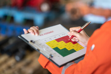 Action of a person is using ballpoint pen to marking on the risk assessment matrix table at 