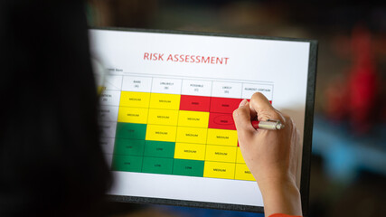 Wall Mural - action of a person is using ballpoint pen to marking on the risk assessment matrix table at 