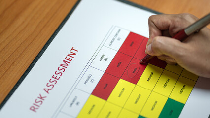 Wall Mural - action of a person is using ballpoint pen to marking on the risk assessment matrix table at 